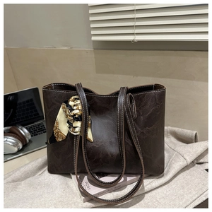 Détail d'un cabas vintage marron foncé avec foulard en soie à motif dans un décor urbain