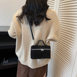 Chic black matte crossbody bag with heart-shaped silver zippers shown on beige sweater