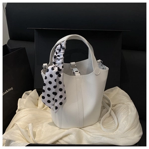 Detail of white lychee leather bucket bag with polka dot silk scarf on the handle