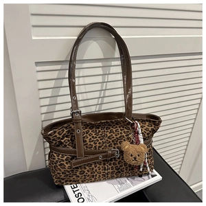 Detail of leopard print tote bag with brown faux leather straps and plush bear charm