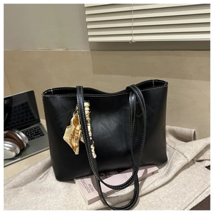 Détail du sac cabas noir avec coutures blanches et foulard décoratif sur un bureau