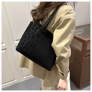 Chic black leopard print tote bag with plush fabric texture shown in a street style look