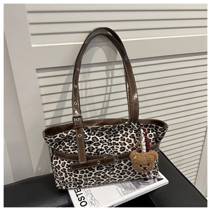Detail of leopard print tote bag with brown leather straps and plush bear charm