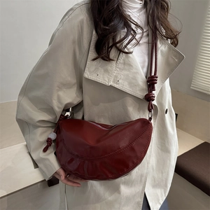 Sac hobo rouge foncé en cuir avec bandoulière à nœuds et design incurvé minimaliste