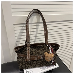 Detail of leopard print canvas tote with brown leather straps and plush bear charm