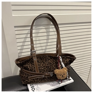 Detailed view of leopard print tote bag with brown leather straps and plush bear charm