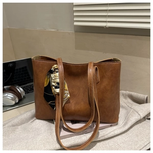 Gros plan du sac cabas en similicuir marron vintage avec coutures blanches et détail foulard floral