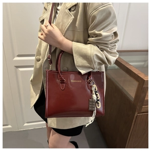 Détail du sac à main bordeaux brillant avec breloque chocolat et sangle chaîne épaisse