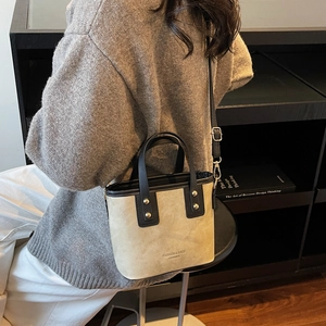 Fashion beige suede bucket bag with black leather trim and metal rivet details