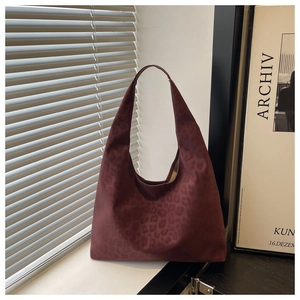 Close-up of deep wine red leopard print suede tote bag with soft indoor lighting details