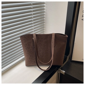 Detailed view of large brown leopard print suede tote bag in a sunlit interior