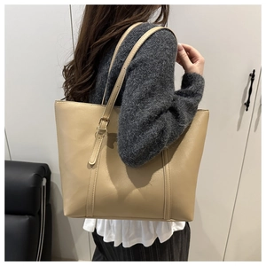 Detail of adjustable shoulder strap and gold buckle on a beige faux leather tote bag
