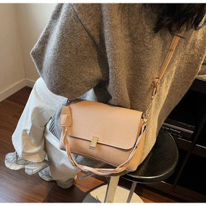 Detail of beige faux leather crossbody bag with woven handle and metallic square buckle