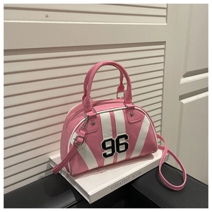 Detail of pink and white Boston bag with '96' embroidery and star rivets on a book