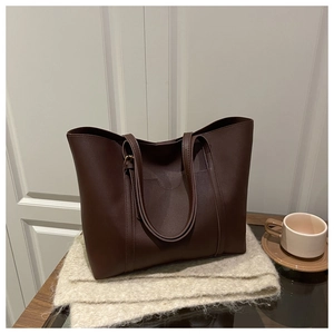 Detailed close-up of a large coffee-brown tote bag with matte texture and long shoulder straps