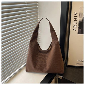 Detail of dark brown leopard print tote bag with suede texture in minimalist setting