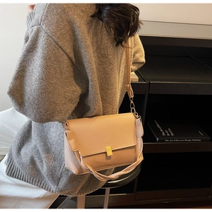 Detail of light beige crossbody bag with golden square lock and braided handle on model