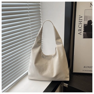 Close-up of minimalist white shoulder bag with wide strap and smooth faux leather finish