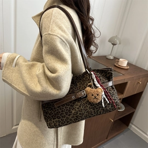 Fashionable leopard print tote bag with brown leather straps and plush bear charm decor