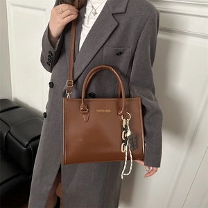 Sac fourre-tout marron brillant avec bandoulière et accessoire pendentif chocolaté