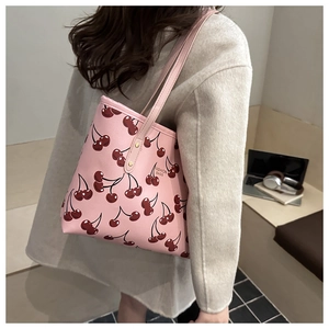 Gros plan du sac cabas rose avec imprimé cerises, cuir texturé et rivets dorés