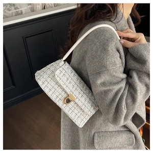 Détail du sac bandoulière en tweed avec fermoir doré porté sur un manteau gris