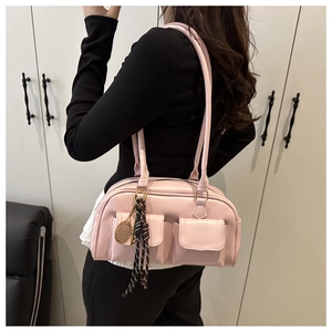 Dettaglio borsa a spalla rosa chiaro con doppie tasche frontali e ciondolo a racchetta