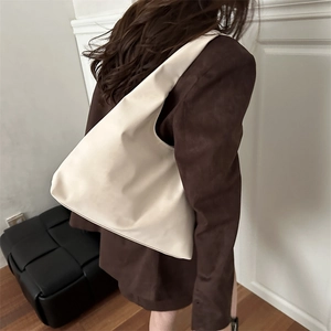 Minimalist cream leather hobo tote bag with wide strap worn by a model in casual style