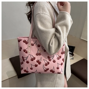 Détail du cabas rose avec imprimé cerises et rivets dorés sur un manteau en laine