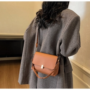 Detail of orange crossbody bag with gold buckle on grey tweed coat for autumn style