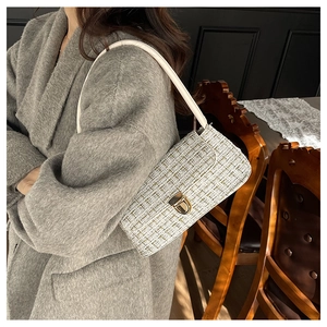 Détail du sac sous le bras en tweed avec boucle dorée sur un mannequin en manteau