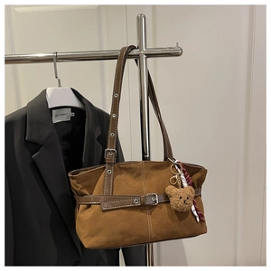 Detail of vintage brown suede shoulder bag with belt buckle and cute teddy charm