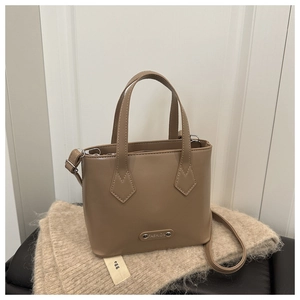 Dettaglio della borsa a secchiello in PU marrone su coperta con logo FASHION in metallo