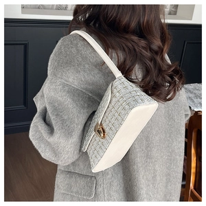 Détail du sac bandoulière en tweed avec fermoir rotatif doré élégant sur un manteau gris