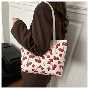 Détail d'un sac cabas blanc avec motifs cerises et texture de couture en cuir