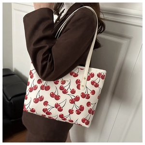 Détail de l'imprimé cerise rouge sur cabas blanc en cuir avec lettrage doré chic