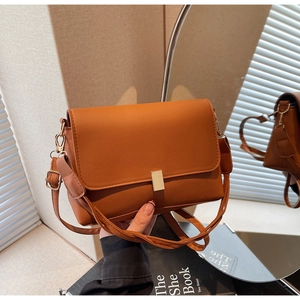 Detailed view of caramel leather crossbody bag featuring gold metal buckle and matte finish