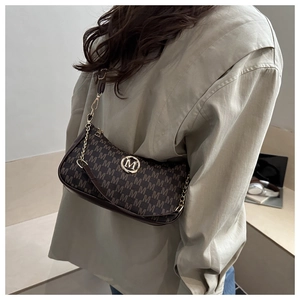 Braune Retro-Schultertasche mit M-Monogramm und goldener Kette an einem Model
