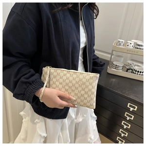 Close-up of beige M-pattern monogram clutch bag with gold zipper and wrist strap detail