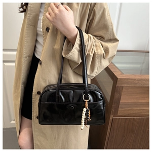 Chic black glossy underarm bag with beaded charm styled with a khaki trench coat