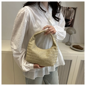 Gros plan sur un sac hobo en paille tressée montrant la texture en maille beige