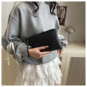 Close-up of a stylish grey geometric polka dot clutch bag with a zipper and wrist strap