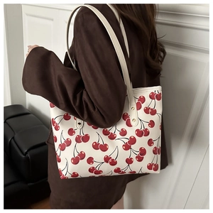 Vue détaillée d'un grand sac fourre-tout crème avec des motifs de cerises rouges vifs