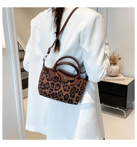 Detail of leopard print handbag with brown leather handle and circular metal buckle detail