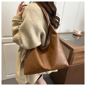 Macro detail of dark brown retro tote bag with textured matte leather and soft pleats