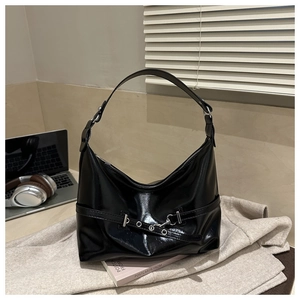 Dettaglio della borsa hobo nera lucida con fibbie argentate su lana grigia