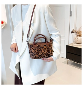 Detail of a leopard print crossbody bag with brown leather handles and gold metal clasp
