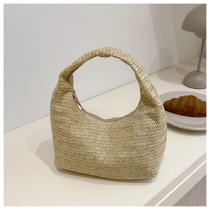 Détail d'un sac hobo en paille tressée naturelle avec fermeture éclair sur une table