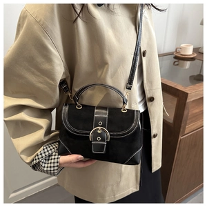 Detail of black crossbody bag with white contrast stitching and gold buckle closure