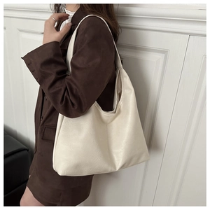 Detail of minimalist cream oversized hobo tote bag shown on model with brown blazer